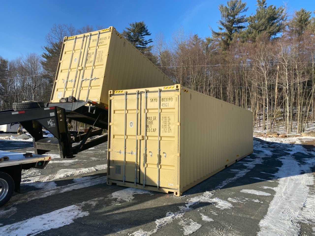 Large yellow shipping container on a flatbed truck with a forest in the background