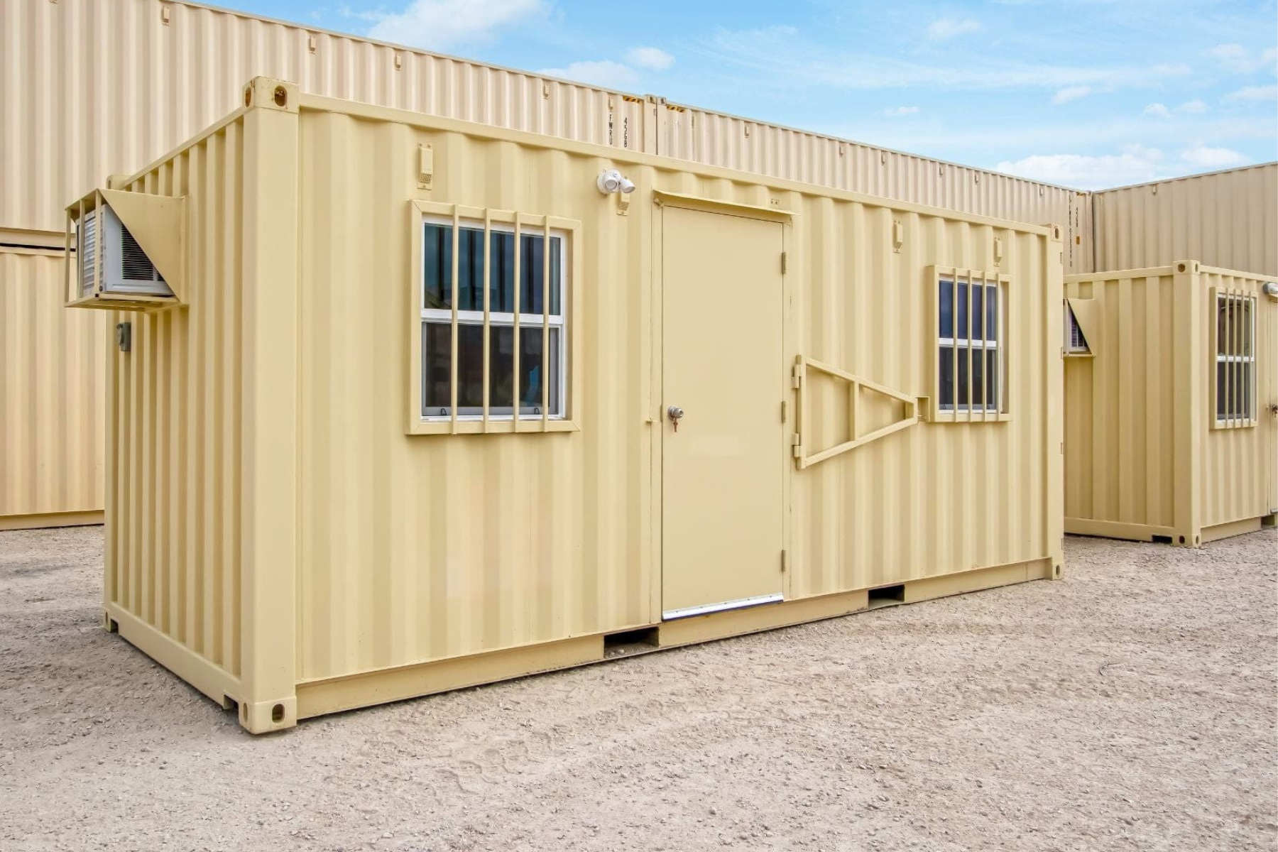 Beige modular building with windows and a door on a clear day.